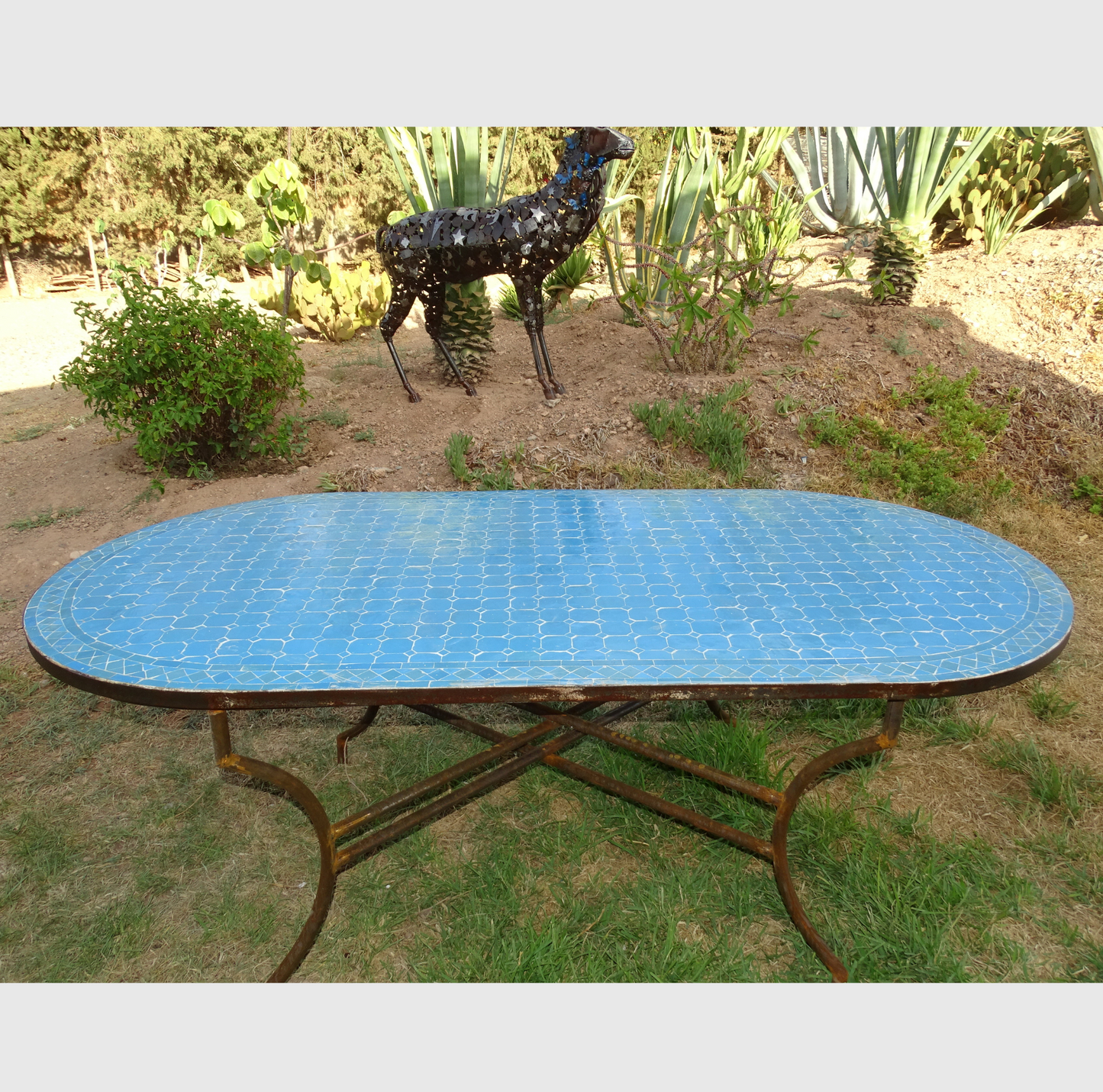 Table ovale en zellige bleu, 200x100 cm, mosaïque artisanale, piètement en fer forgé.