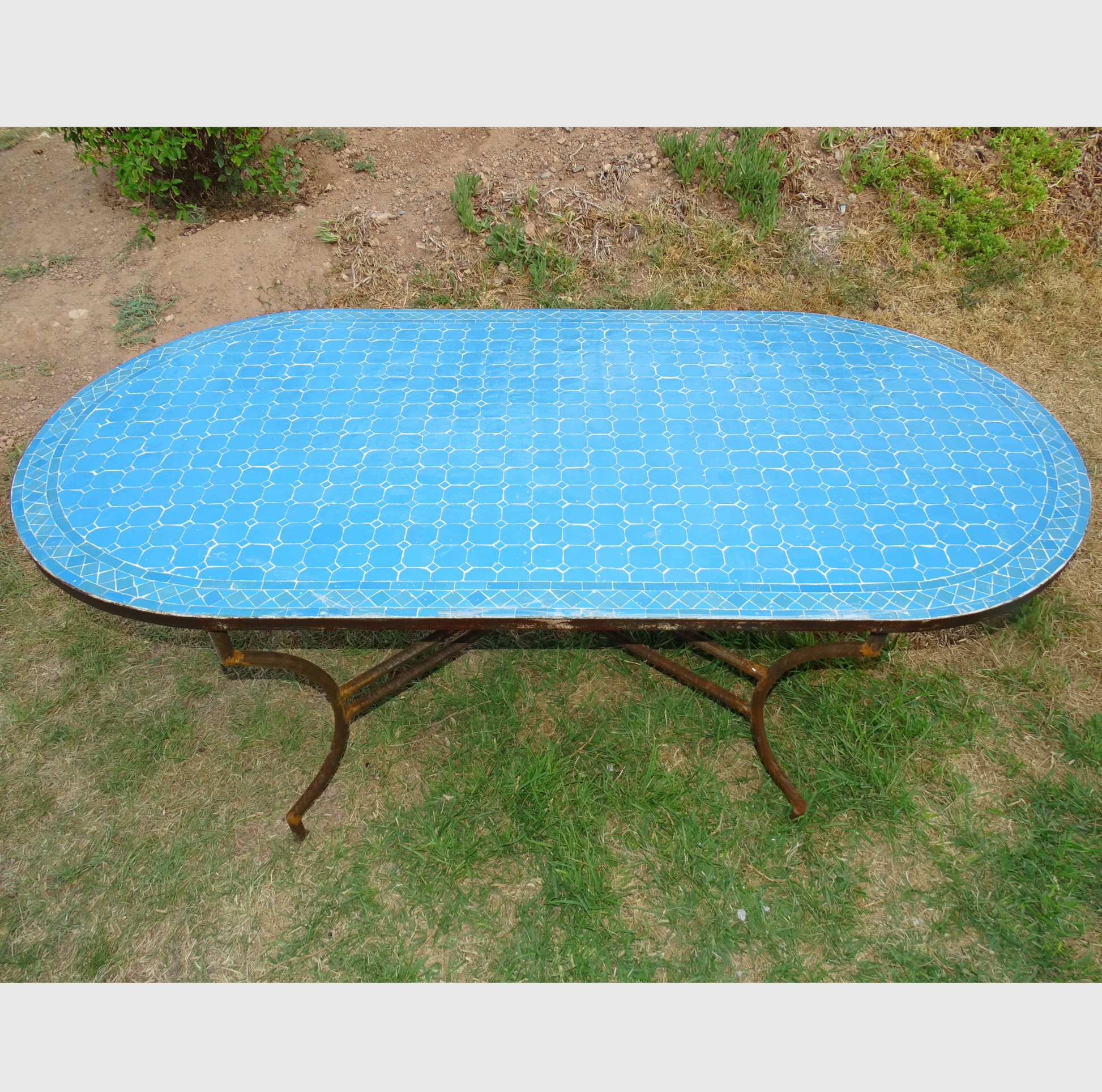 Table ovale en zellige bleu, 200x100 cm, mosaïque artisanale, piètement en fer forgé.