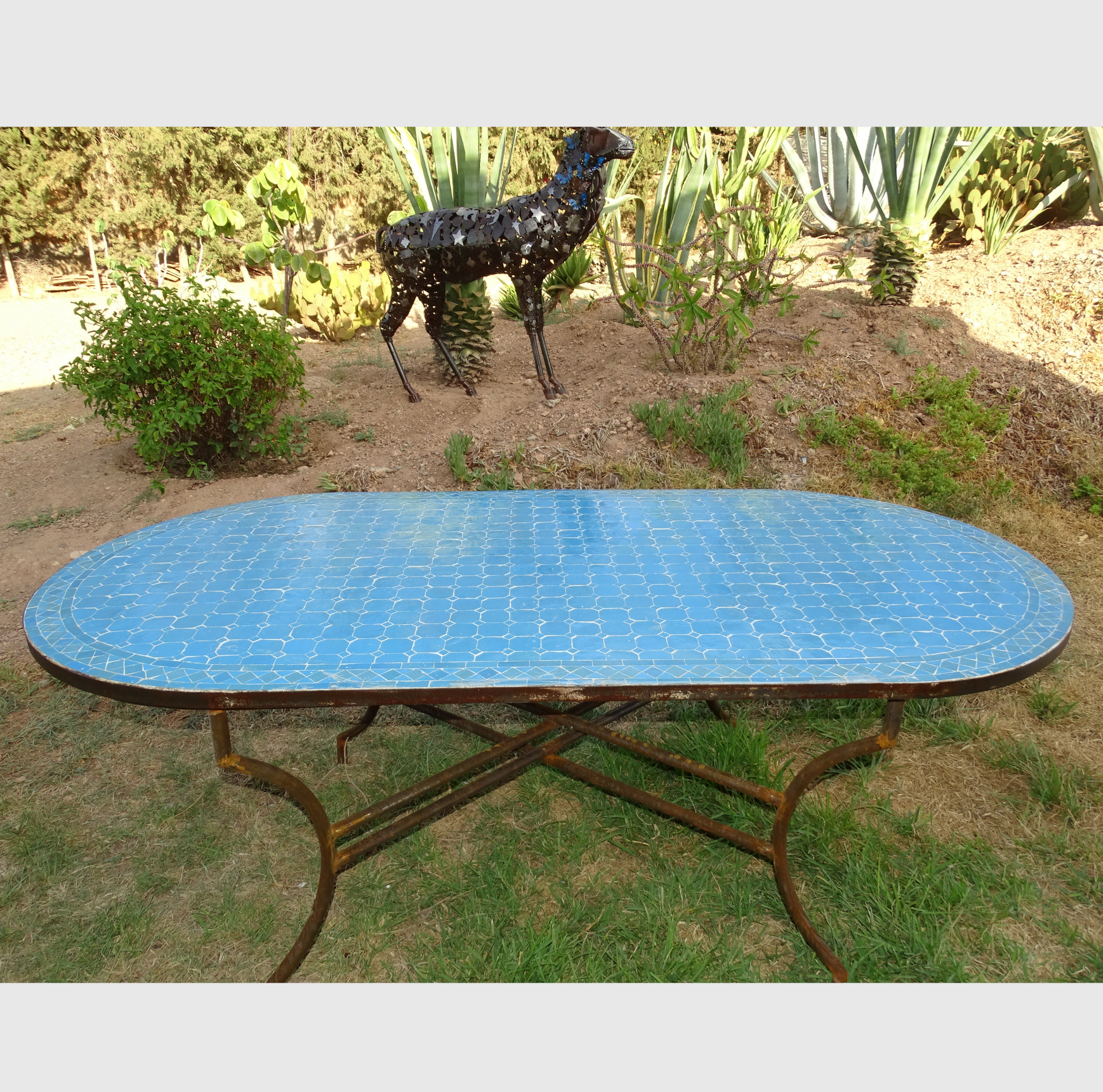Table ovale en zellige bleu, 200x100 cm, mosaïque artisanale, piètement en fer forgé.