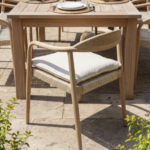 Chaise en teck massif NINA installée autour d'une table de salle à manger, sur une terrasse ou dans un jardin