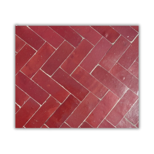 Détail du plateau en zellige marocain bordeaux posé à la main révélant texture minérale et nuances profondes