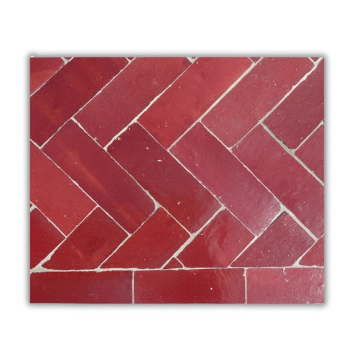 Détail du plateau en zellige marocain bordeaux posé à la main révélant texture minérale et nuances profondes