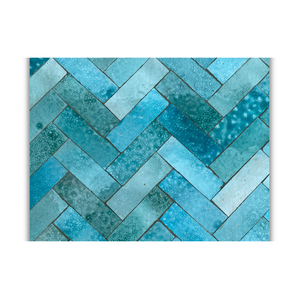 Détail rapproché des carreaux de zellige bleu ciel posés à la main sur table ronde extérieure avec texture artisanale visible