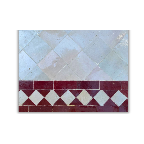 Détail du plateau en mosaïque marocaine zellige bordeaux et beige posé à la main sur table rectangulaire