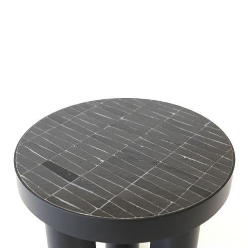 Détail du carrelage zellige noir marocain et du pied en fer forgé révélant la texture artisanale