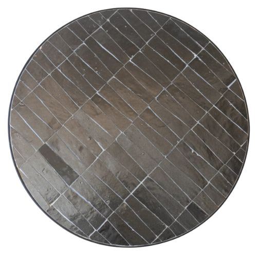 Détail du carrelage zellige noir marocain et du pied en fer forgé révélant la texture artisanale