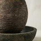 Fontaine de jardin forme œuf finition pierre naturelle installée sur terrasse extérieure