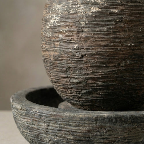 Fontaine ovale de jardin installée dans un espace paysager avec végétation et sol naturel