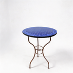 Détail du pied en fer forgé finition rouillée sous table ronde en zellige bleu pour extérieu