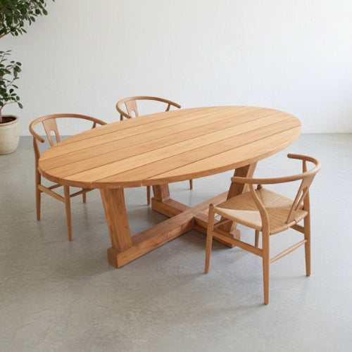 Grande table ovale en teck massif installée dans une salle à manger, sur une terrasse ou dans un jardin