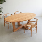 Grande table ovale en teck massif installée dans une salle à manger, sur une terrasse ou dans un jardin