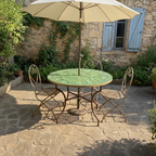 Table marocaine ronde en zellige vert avec trou parasol installée dans un jardin méditerranéen