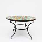Table ronde extérieure en zellige multicolore Ø100 cm sur fond blanc avec pied en fer forgé rouillé