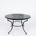 Table ronde extérieure en zellige noir Ø120 cm sur fond blanc avec structure en fer forgé finition rouillée