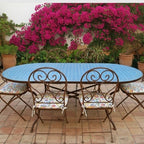 Table ovale en zellige marocain bleu moyen avec pied pliable en fer forgé noir installée sur terrasse extérieure