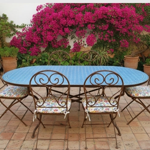 Table ovale en zellige marocain bleu moyen avec pied pliable en fer forgé noir installée sur terrasse extérieure