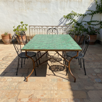 Table rectangulaire en zellige marocain nuances vert bleu et brun avec pied pliable en fer forgé posée en terrasse