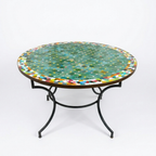 Table ronde extérieure en zellige vert Ø120 cm sur fond blanc avec frise multicolore et fer forgé rouillé