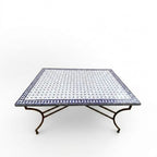 Table en zellige 150 × 100 cm Blanc avec cabochons bleus – Table artisanale marocaine avec pied pliable en fer forgé rouillé